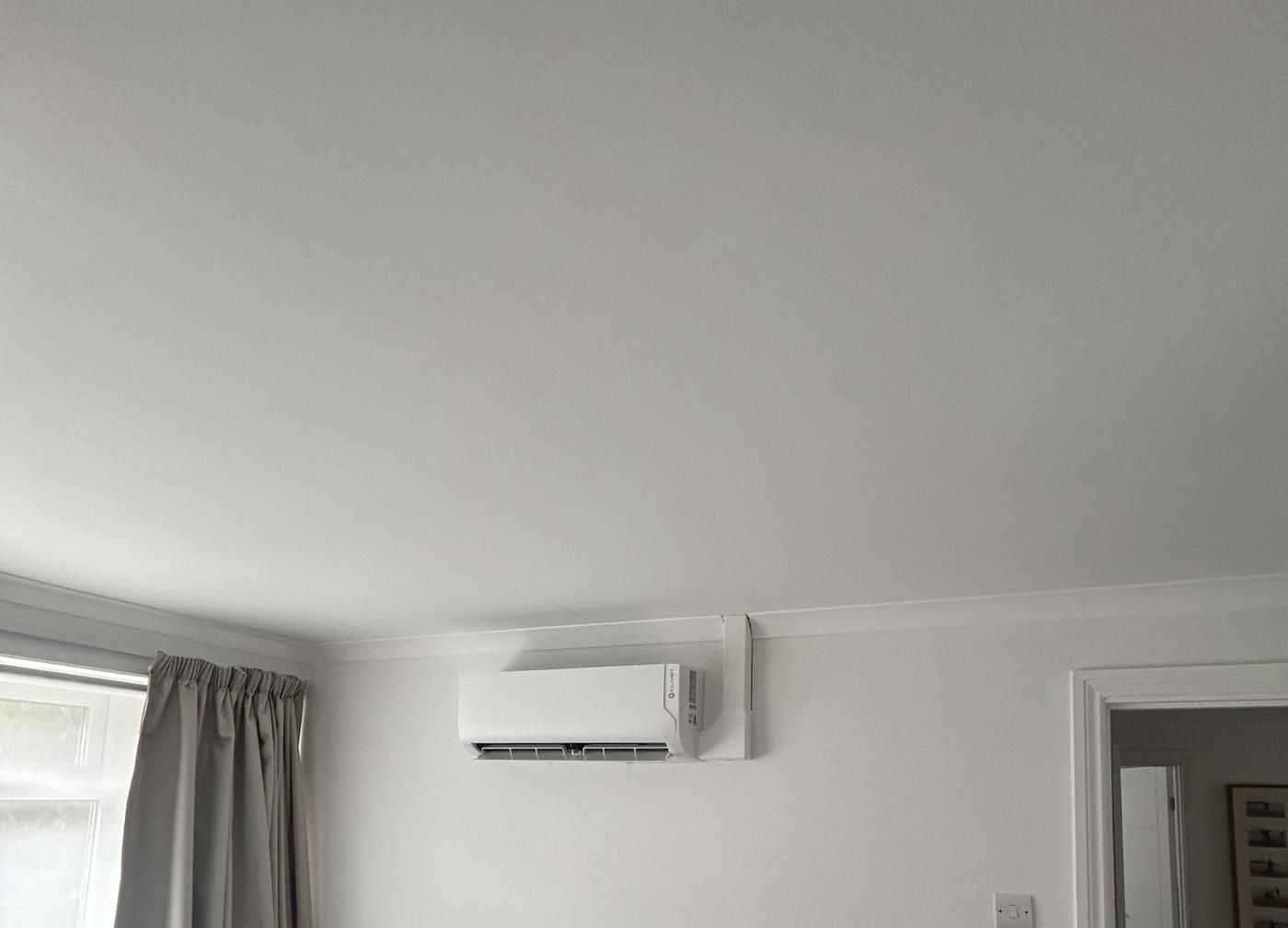 Wall mounted air conditioning unit with white trunking finished neatly to the cornice