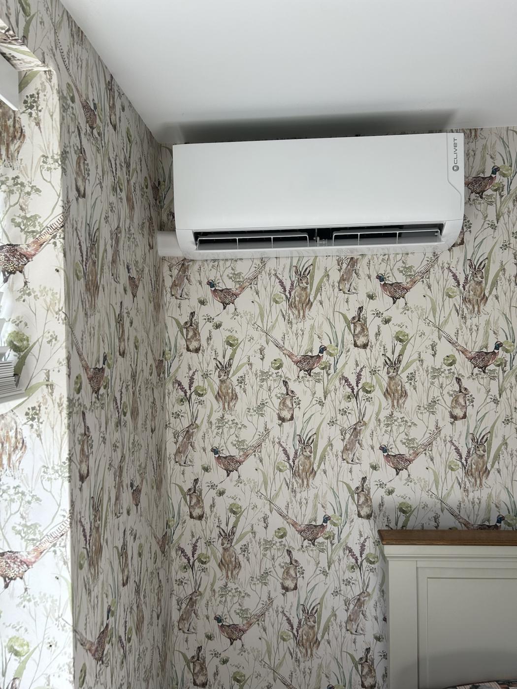 Wall mounted indoor unit in a bedroom with floral wallpaper