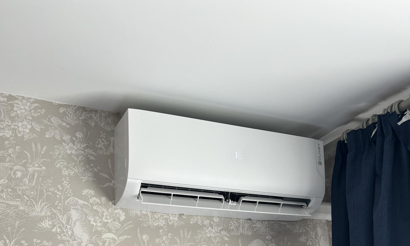 Wall mounted indoor unit in a bedroom, positioned above the window